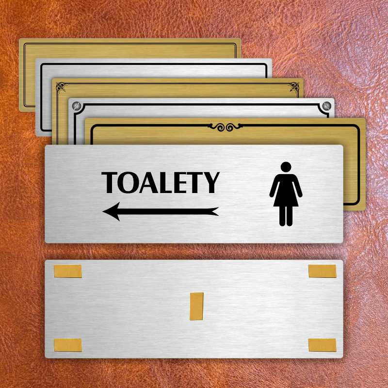 Toalety vlevo ženy, 240x79mm, stříbrná popiska s okrasným rámečkem